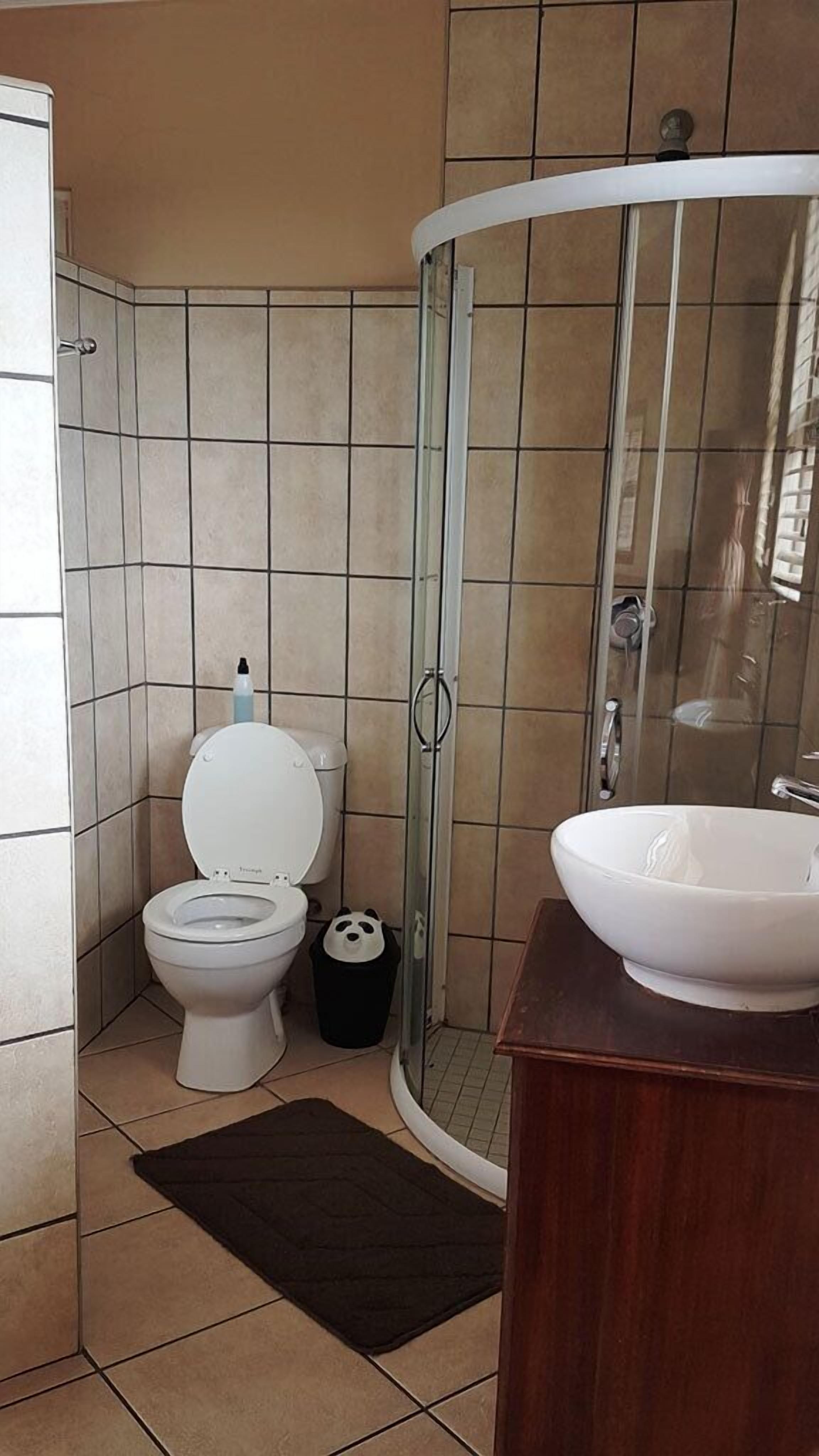 Et badeværelse med toilet, brusekabine i glas og vask.