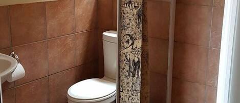 A bathroom with a shower curtain, toilet, sink, and tiled floor.