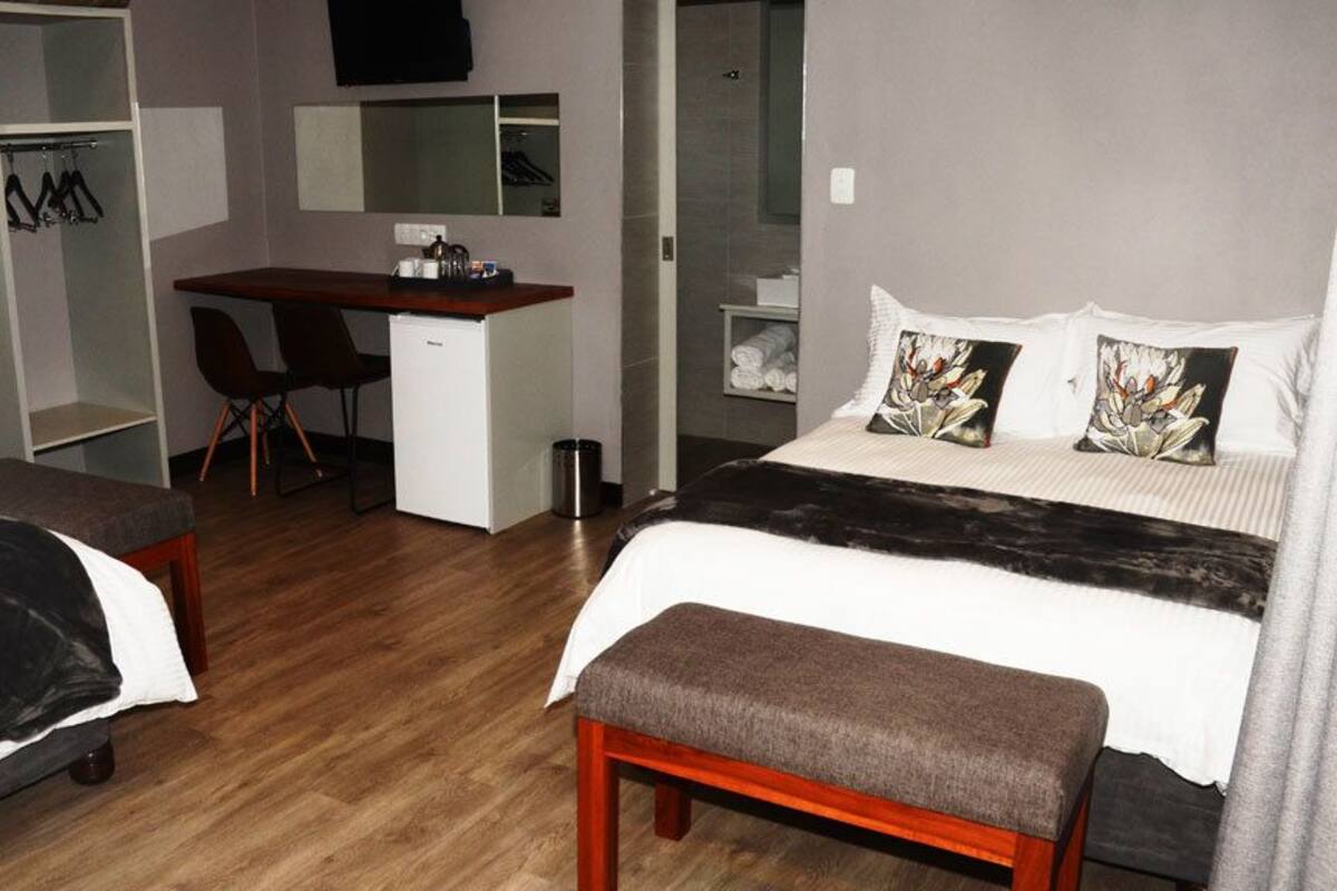 Ein Hotelzimmer mit zwei Betten, einem Schreibtisch, einem Stuhl, einem Kleiderschrank und einer Dusche.