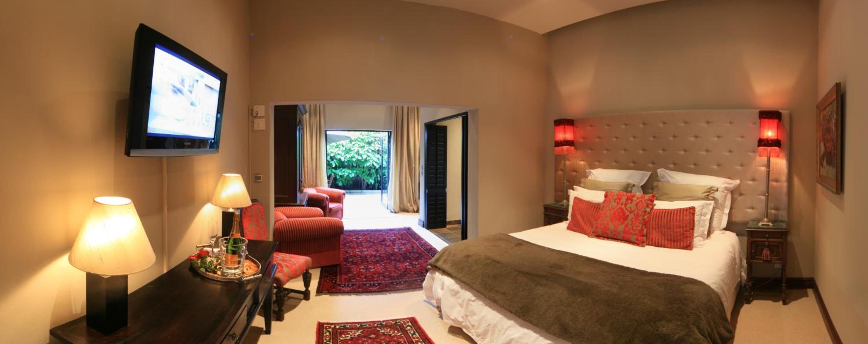A hotel room with a bed, a TV, a desk with a lamp, and a view of the outdoors.