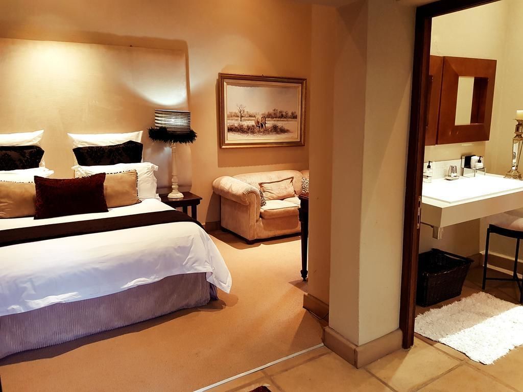 Een hotelkamer met een bed, een stoel, een bureau, een spiegel en een schilderij aan de muur.
