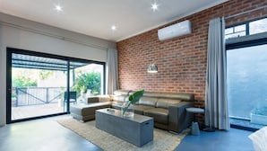 Ein modernes Wohnzimmer mit Backsteinwand, einer Couch, einem Couchtisch und einem großen Fenster.