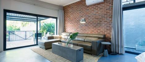A modern living room with a brick wall, a sofa, a coffee table, and a large window.