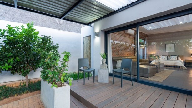 Eine moderne Terrasse im Freien mit Holzdeck, zwei Stühlen und einem Blumentopf.