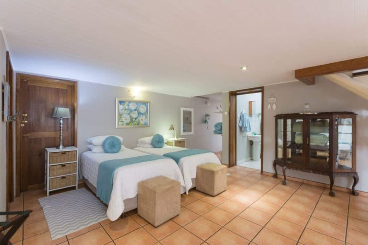 A bedroom with two beds, a wooden cabinet, and a tiled floor.