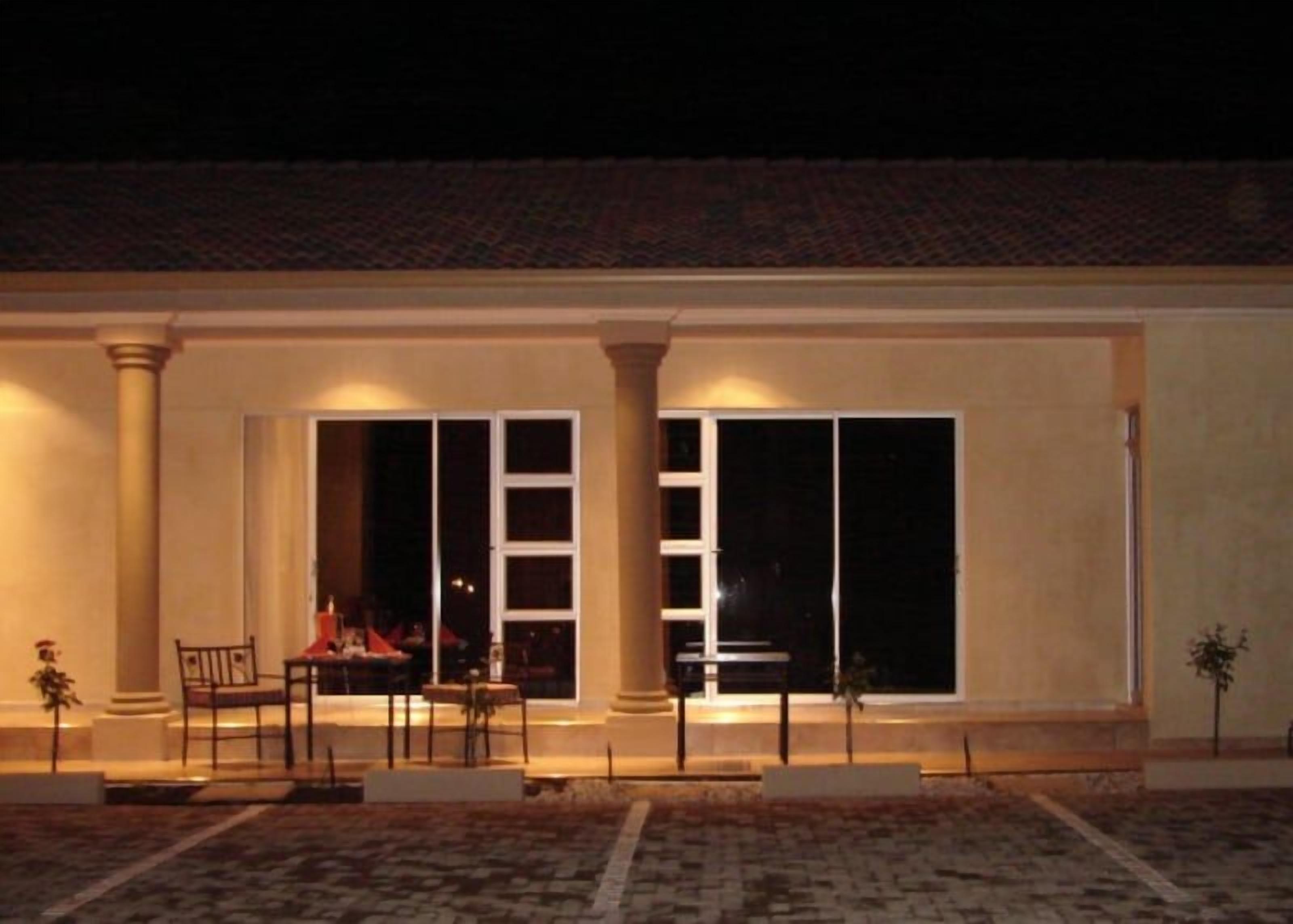 A building with a covered patio area, large windows, and a seating arrangement.
