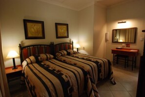 Quarto de hotel com duas camas, uma escrivaninha e uma cadeira.