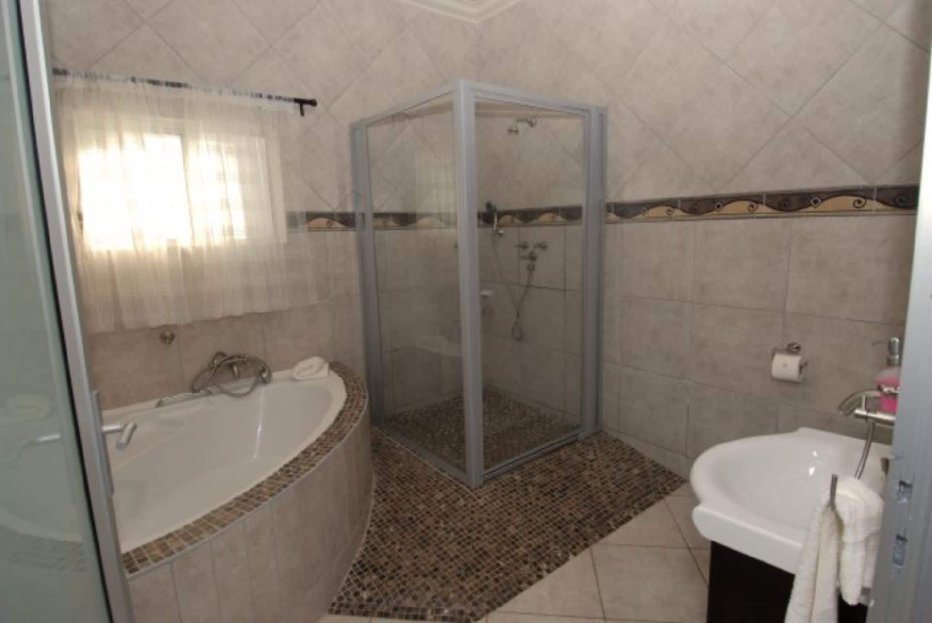 Une salle de bain avec une douche à parois de verre, une baignoire sur pieds et un lavabo.