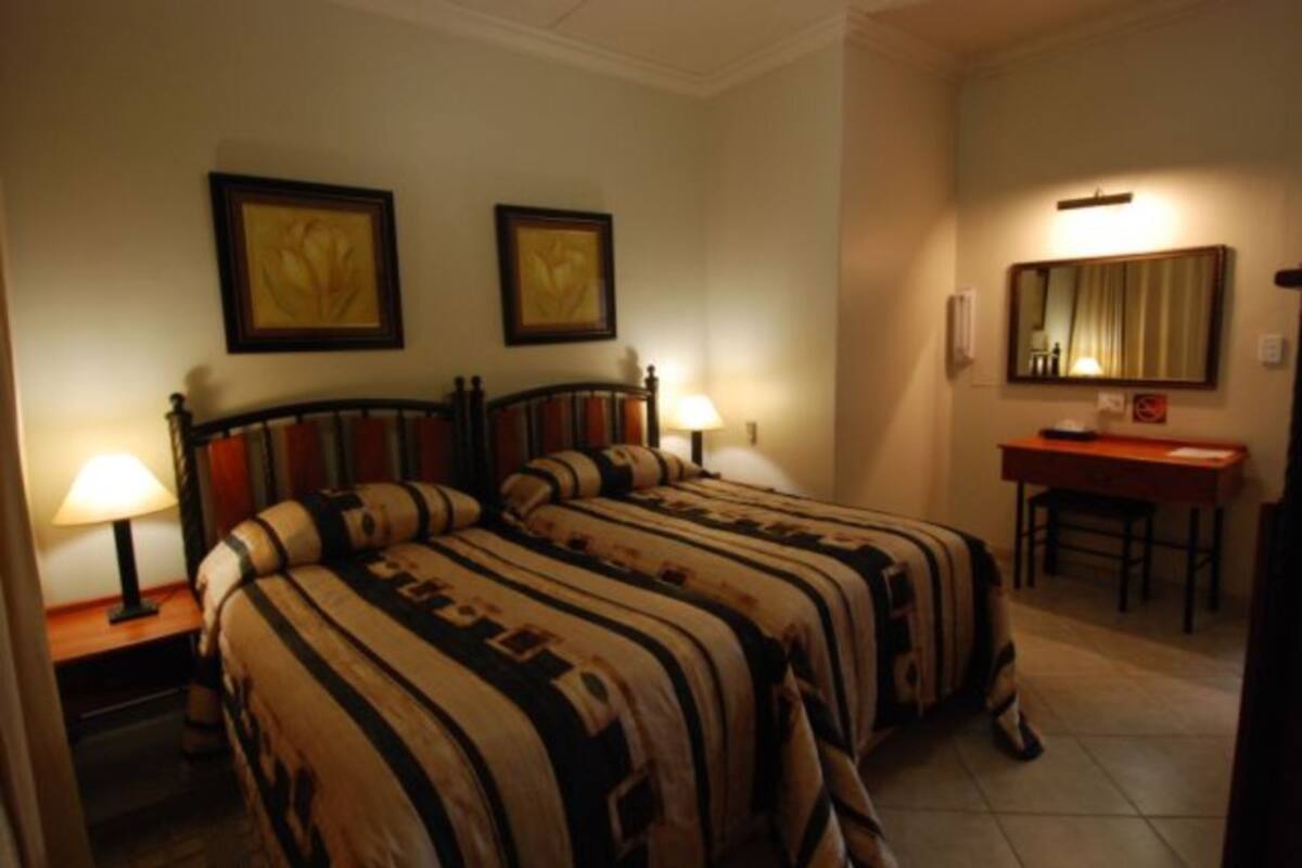 A hotel room with two beds, a desk, and a chair.