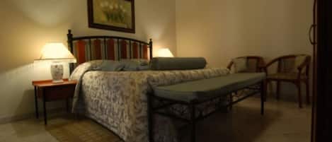 A bedroom with a bed, bedside tables, a chair, and a painting on the wall.