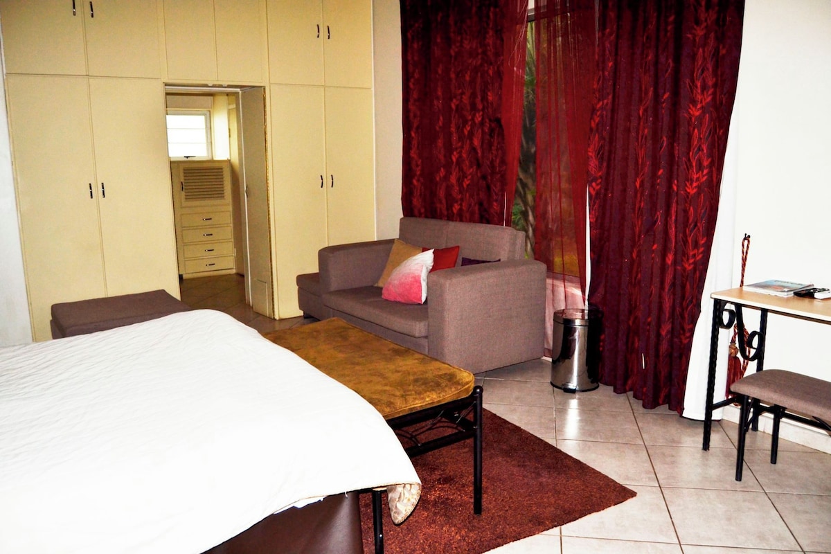 Un dormitorio con cama, sofá, escritorio y armario.