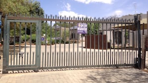 A gated entrance with a sign indicating a 15-minute waiting period. - A Little Guesthouse (Bloemfontein)