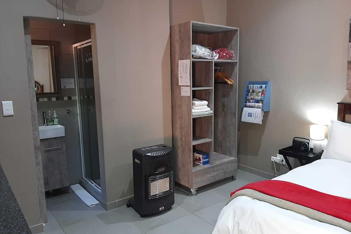 Ein Hotelzimmer mit einem Bett, einem Heizkörper, einem Schrank, einem Spiegel, einem Waschbecken und einem kleinen Tisch mit einer Lampe.