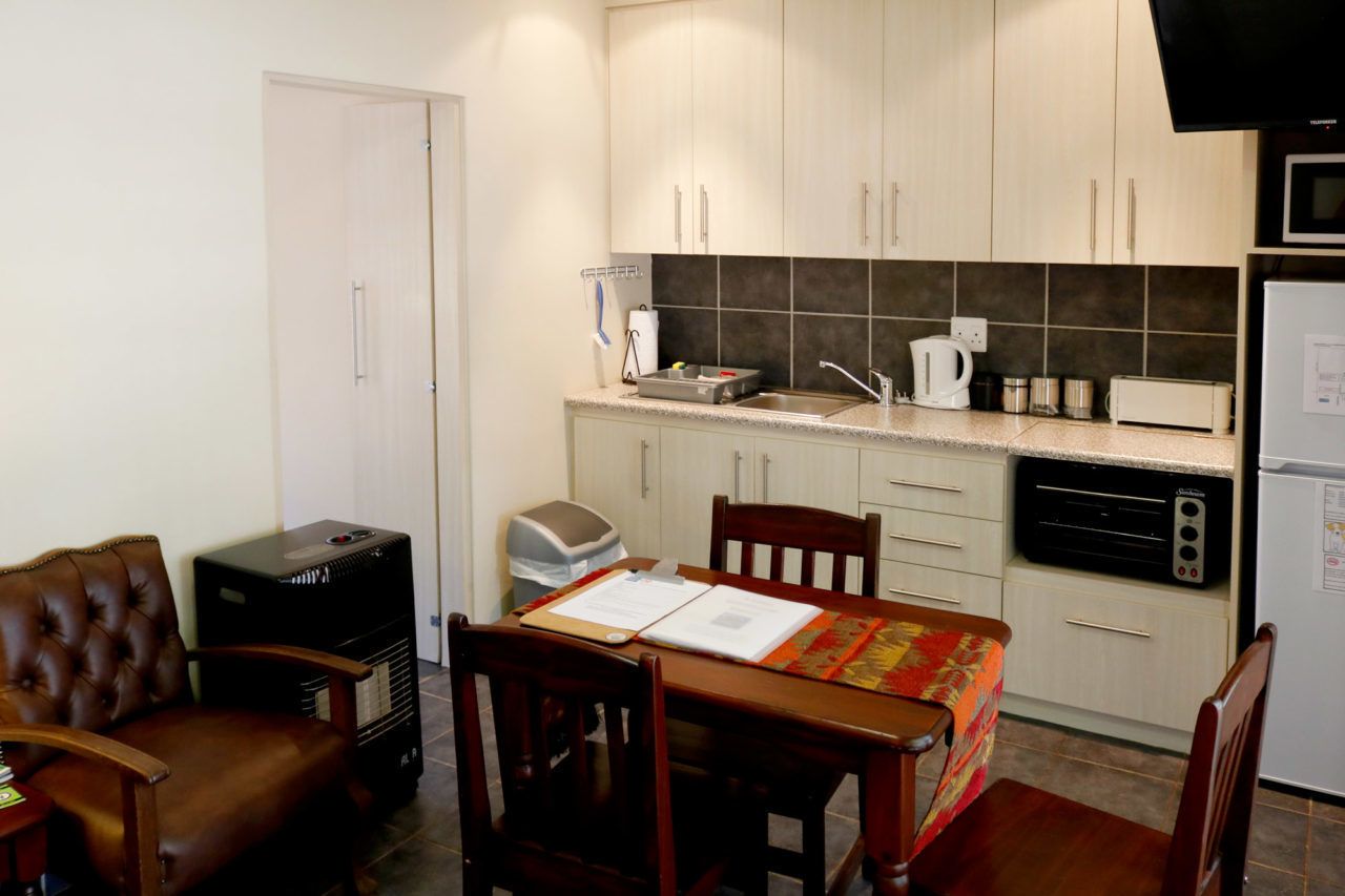 A compact kitchen with a dining table, chairs, a microwave, a toaster, and a refrigerator.