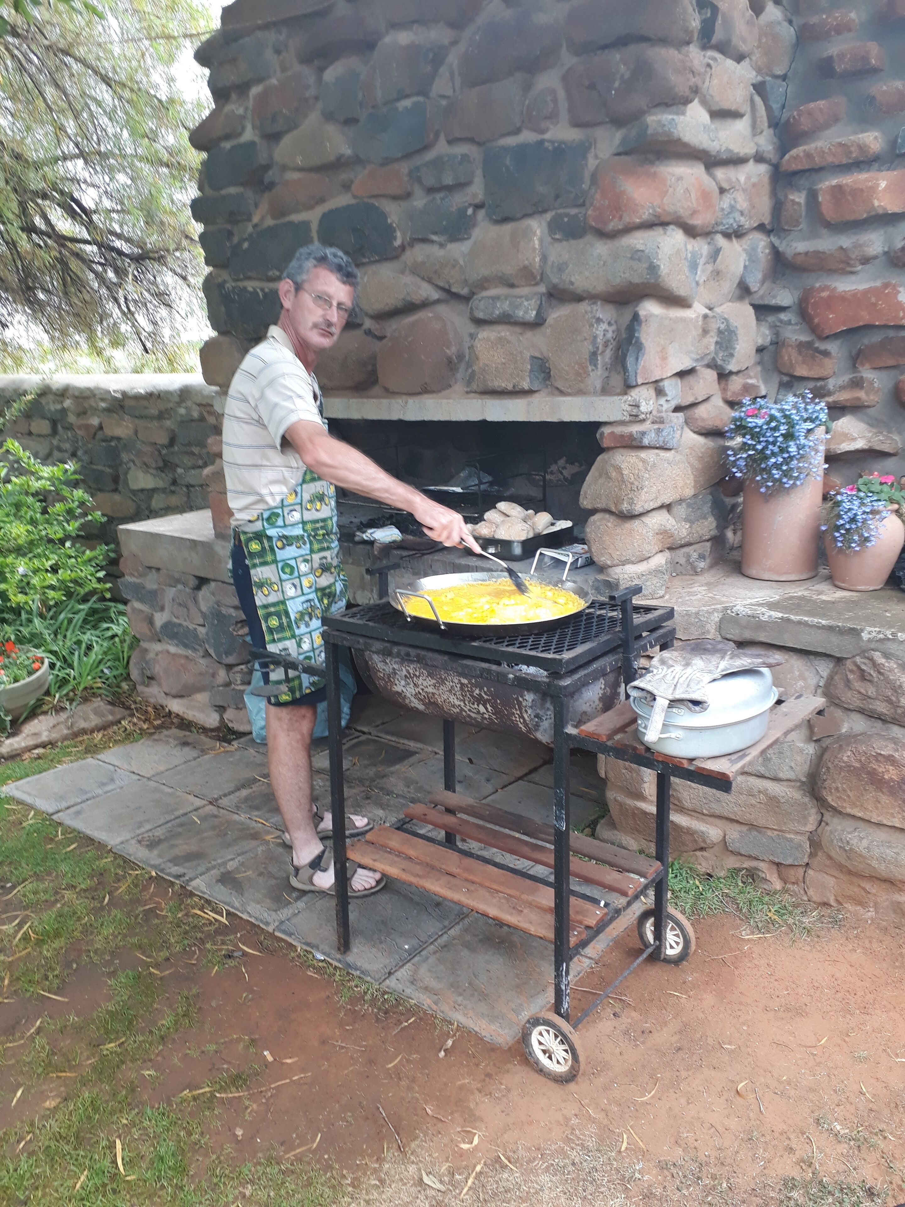 A man cooking on an outdoor grill with a stone fireplace in the background.