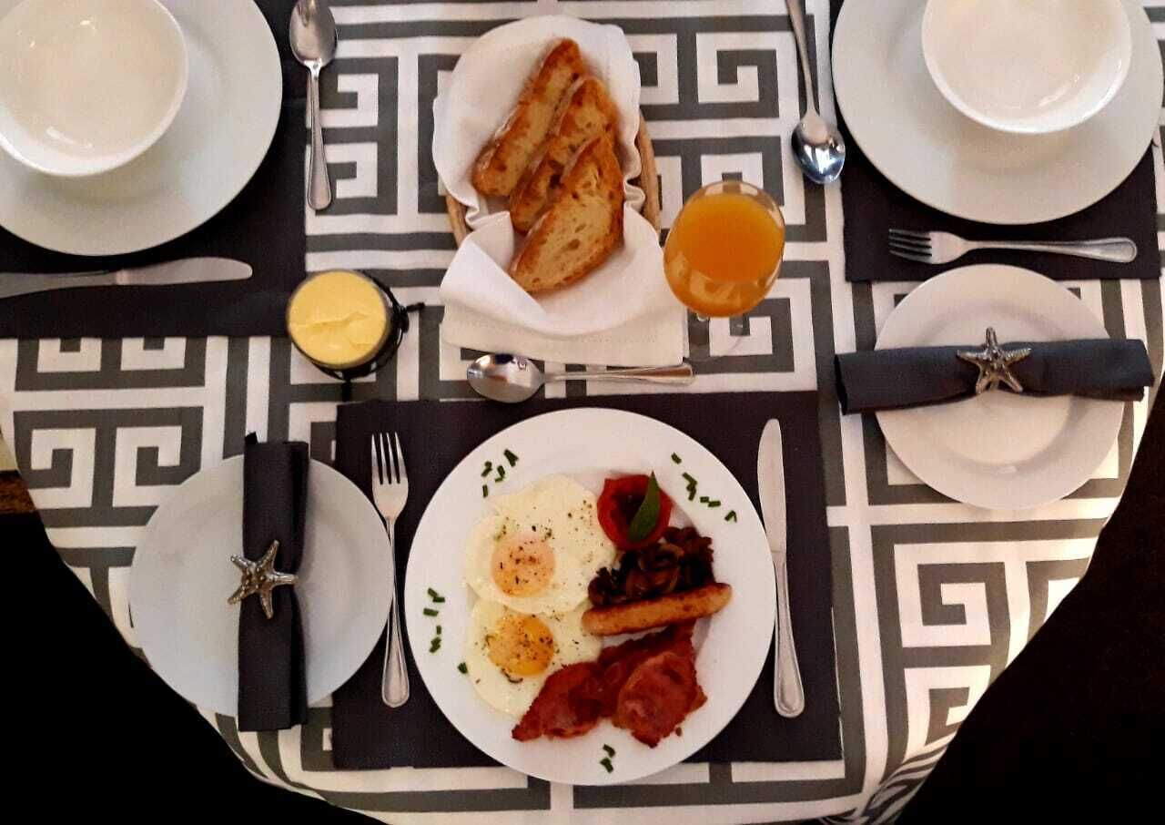A breakfast setting with toast, eggs, bacon, and a side of fruit.