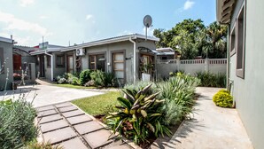 A residential property with a paved driveway, a satellite dish, and various plants. - Beechwood B&B (Durban)
