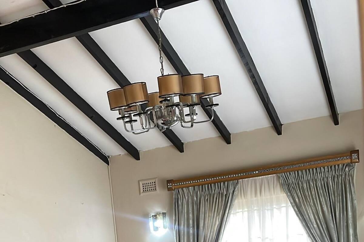 A living room with a sofa, ottoman, TV, and chandelier.
