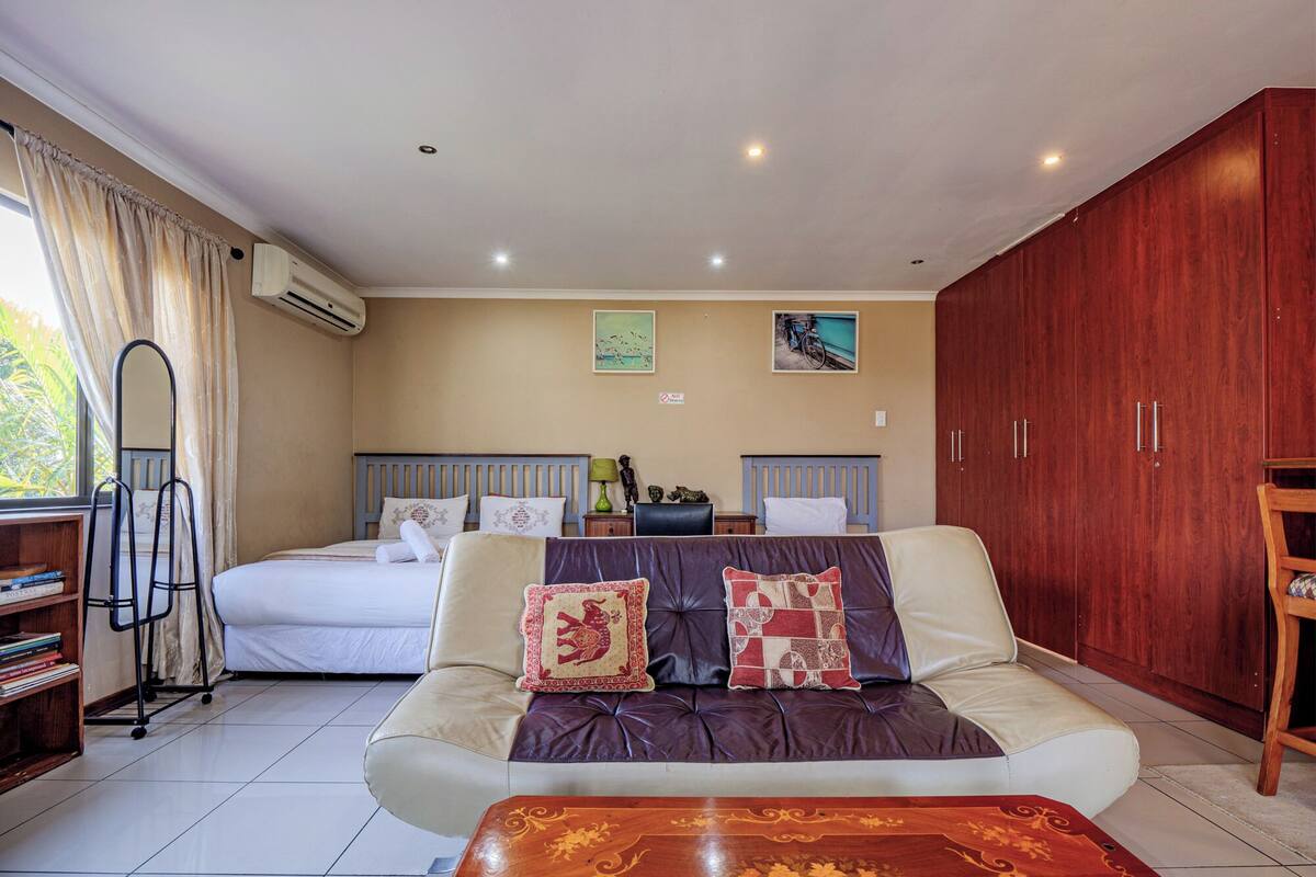 A hotel room with a bed, a sofa, a wooden cabinet, and a small table.