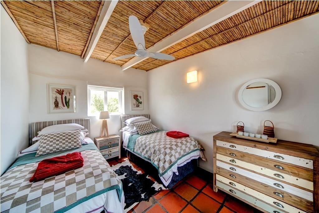 Une chambre avec deux lits, un ventilateur de plafond, une commode en bois et un miroir.