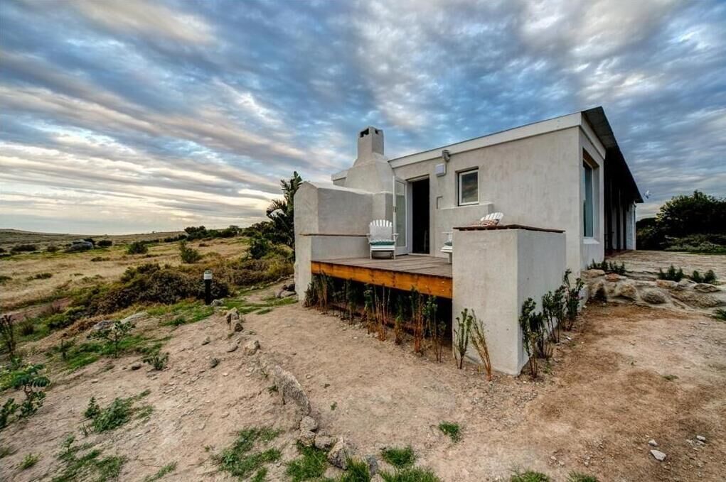 Uma casa moderna com telhado plano, uma pequena varanda e uma janela grande.
