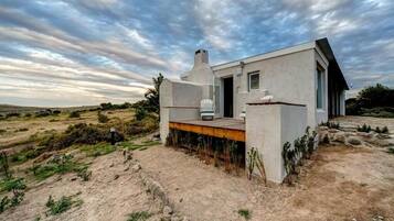 Uma casa moderna com telhado plano, uma pequena varanda e uma janela grande.