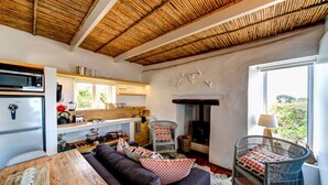 A cozy living area with a sofa, a dining table, a kitchen with a refrigerator, and a fireplace.