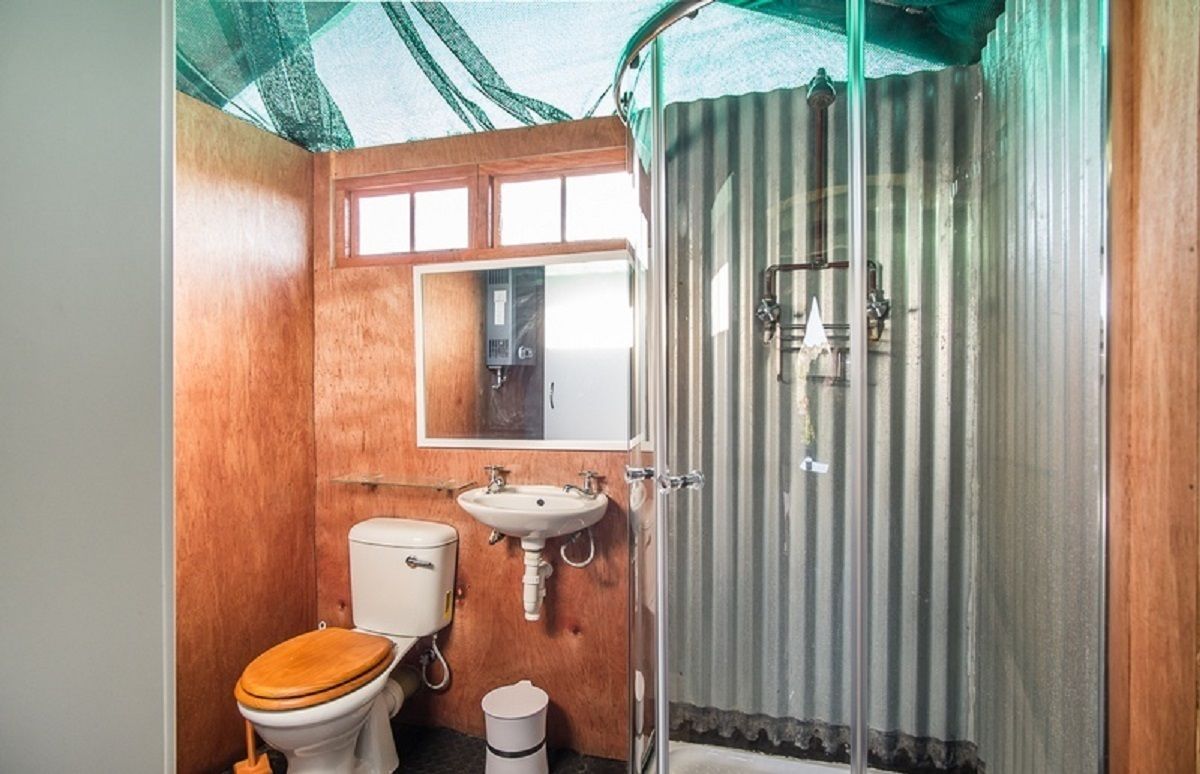 A compact bathroom with a wooden vanity, a toilet, a sink, and a shower enclosure.