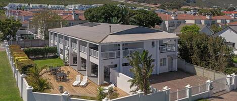 A two-story building with a flat roof, surrounded by a white fence, and featuring a patio with outdoor furniture.