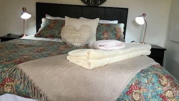 A neatly made bed with a patterned bedspread, pillows with text, and a folded towel.
