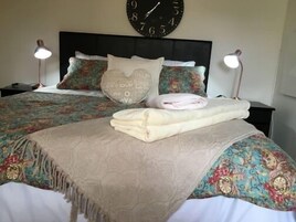 A neatly made bed with a patterned bedspread, pillows with text, and a folded towel.