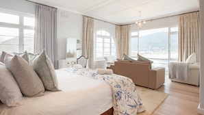 Une chambre spacieuse dotée d’un grand lit, d’un coin salon et offrant une vue sur l’extérieur.