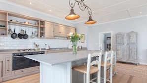Une cuisine moderne avec des meubles en bois, un îlot central et un porte-ustensiles suspendu.