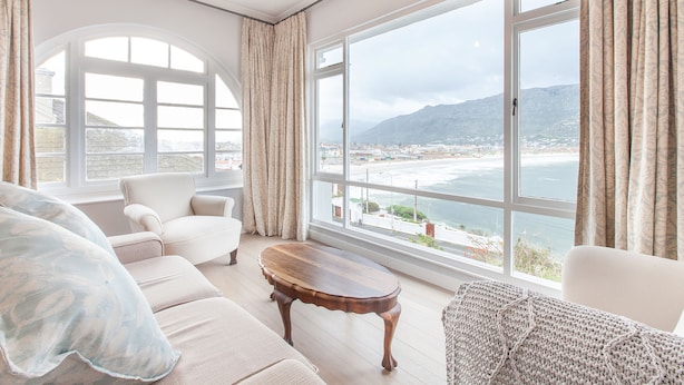 Un salon spacieux doté d’une grande fenêtre offrant une vue sur la mer et les montagnes.