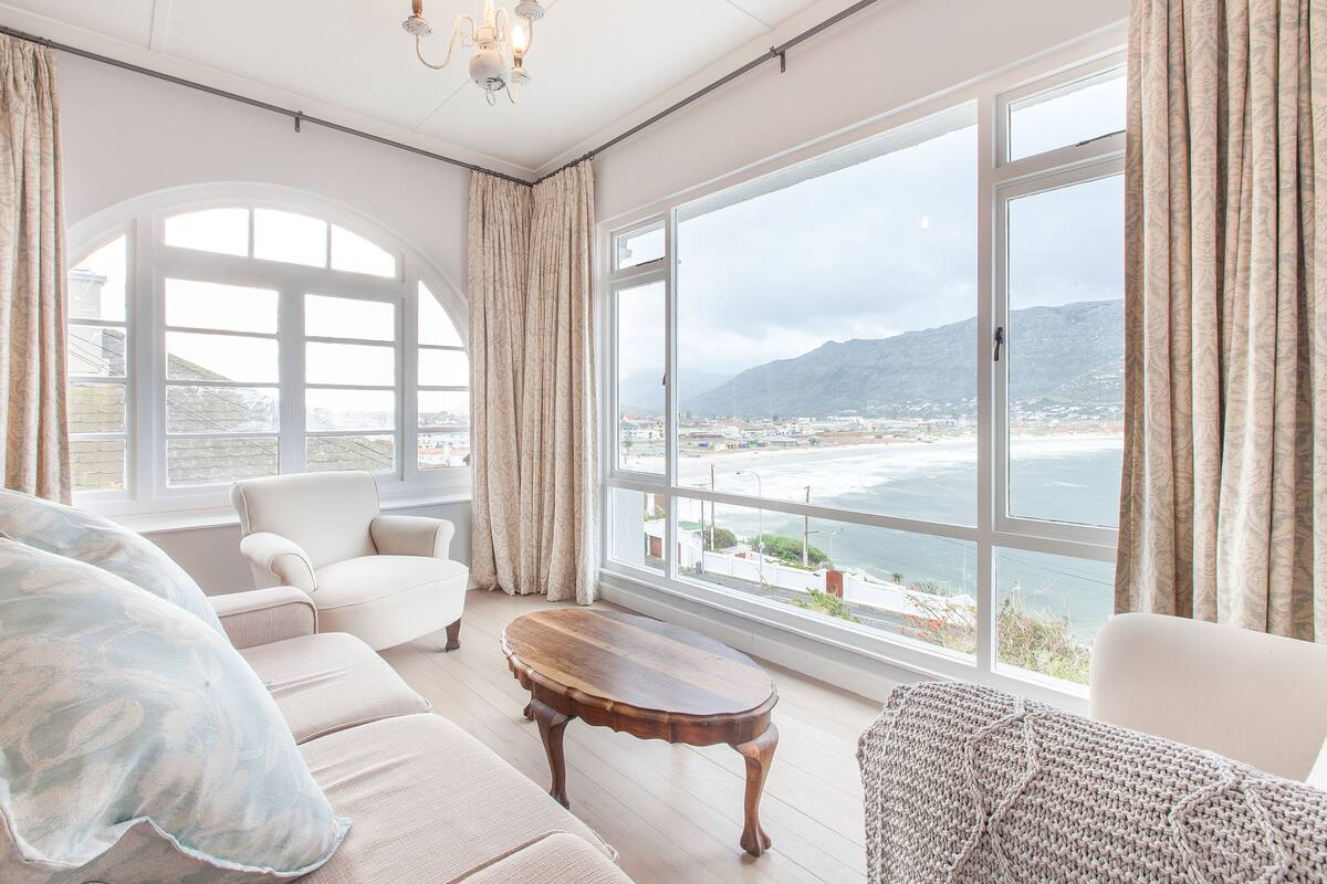 A spacious living room with a large window offering a view of the sea and mountains.