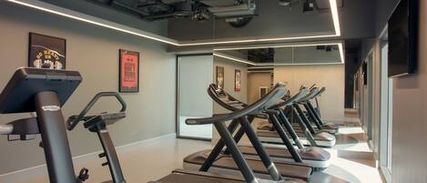 A gym with treadmills and elliptical machines, a mirrored wall, and motivational posters.