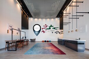 A modern hotel lobby with a reception desk, seating area, and a unique wall art installation.
