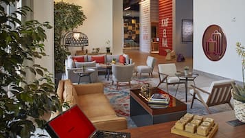 A modern hotel lobby with leather sofas, wooden coffee tables, and a variety of seating options.