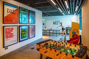 A modern indoor space with a foosball table, framed artwork on the walls, and a casual seating area.