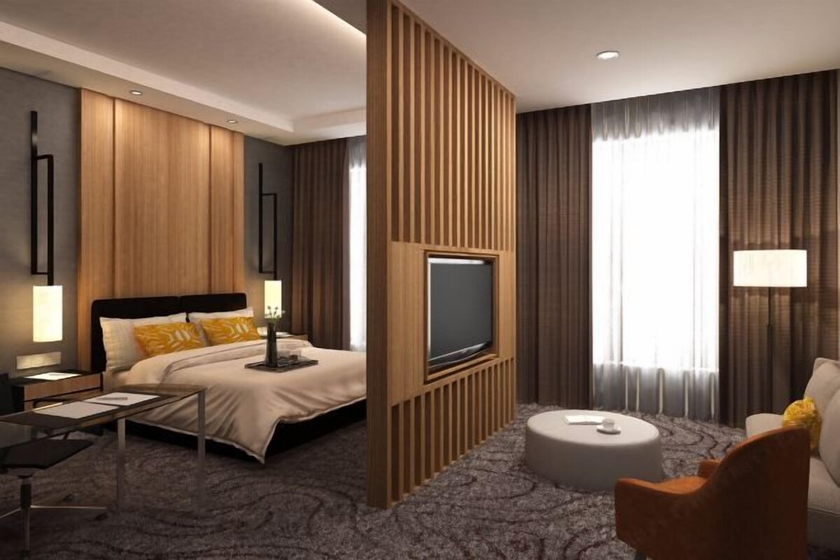 Une chambre d’hôtel moderne dotée d’un grand lit, d’une télévision à écran plat, d’un canapé et d’une table basse.