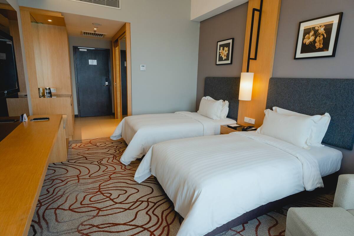 Une chambre d’hôtel avec deux lits, un bureau et un espace de réception.