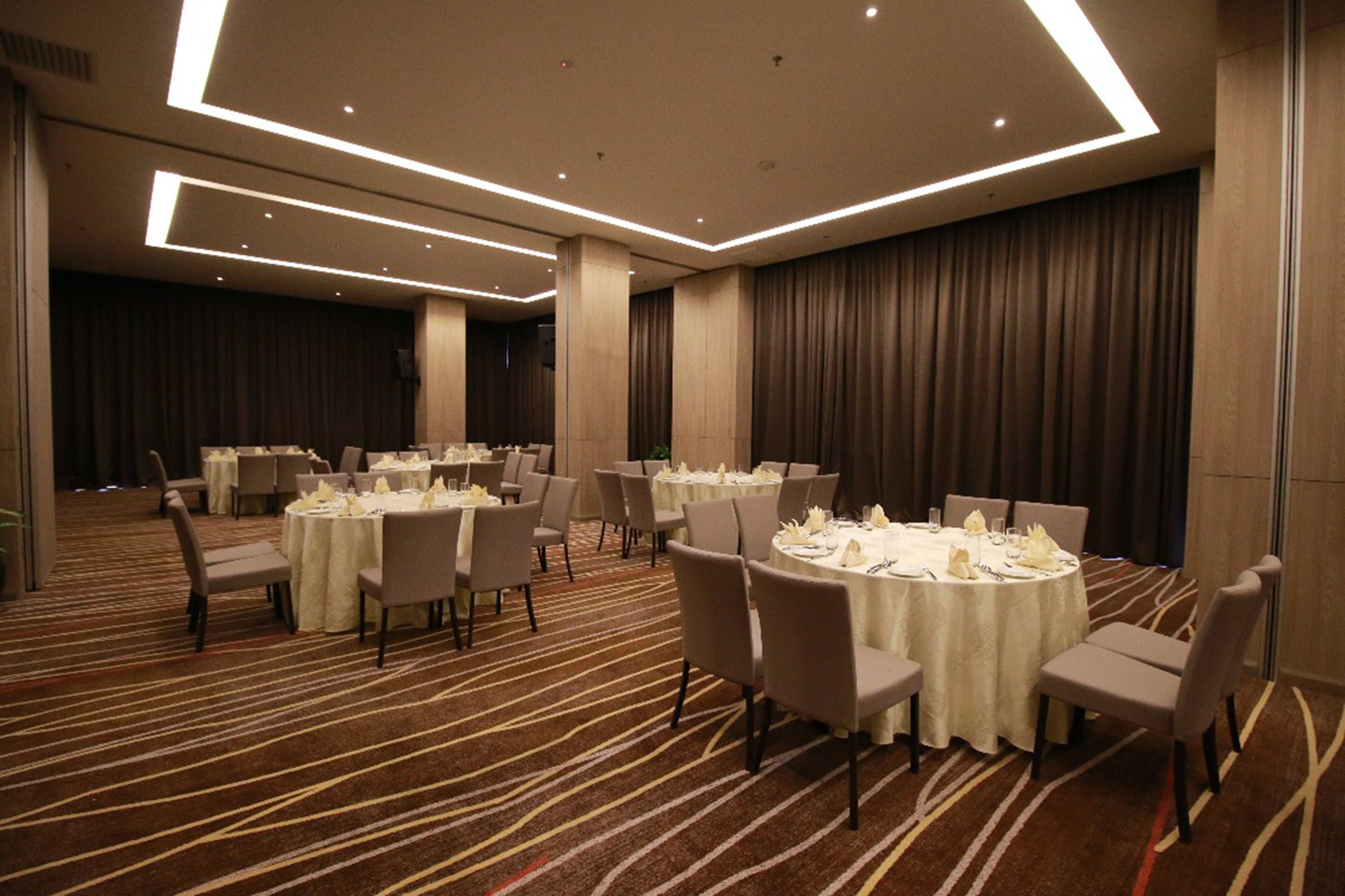 A conference room with round tables, chairs, and a carpeted floor.