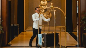 Een hotel lobby met een gepolijste vloer, een receptiebalie en een bedieningspaneel voor de lift bevestigd aan de muur.