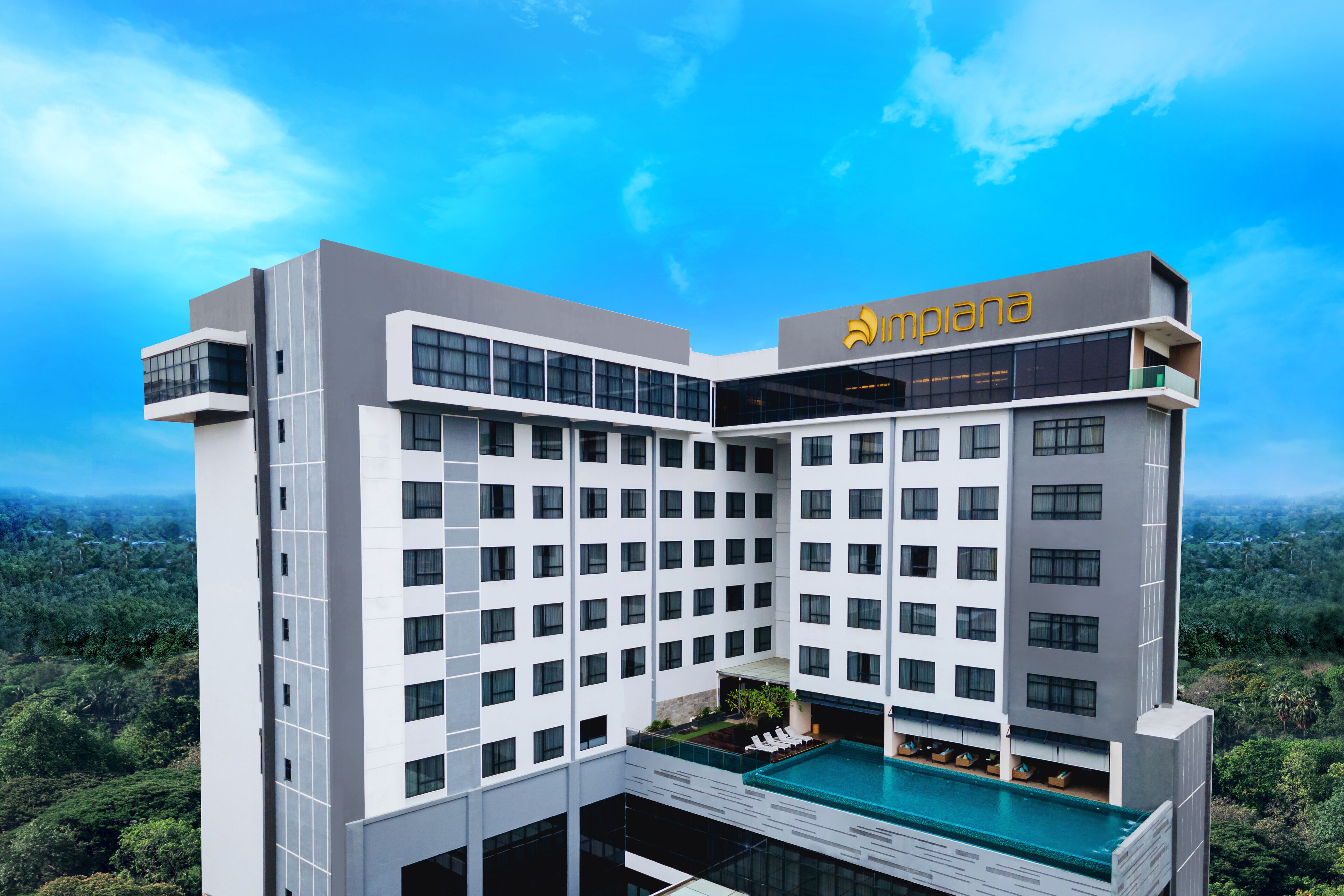 A modern hotel with a rooftop pool, multiple floors, and a name sign.