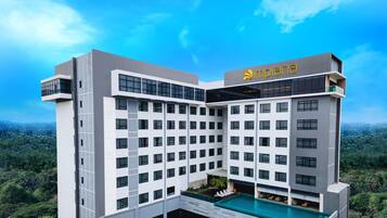 A modern hotel with a rooftop pool, multiple floors, and a name sign.