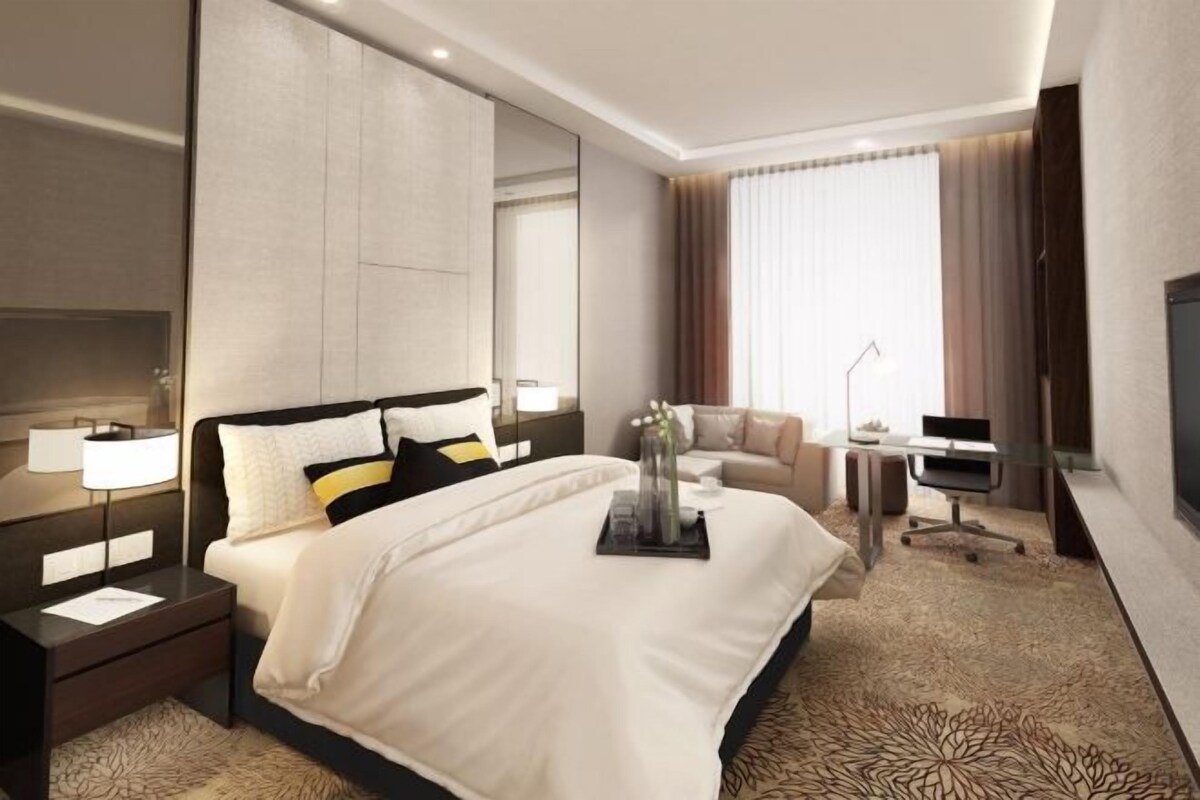 Une chambre d’hôtel moderne équipée d’un grand lit, d’un bureau, d’une chaise et d’un téléviseur.