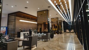 A modern hotel lobby with a reception desk, seating area, and a large mirror. - Impiana Hotel Senai (Senai)