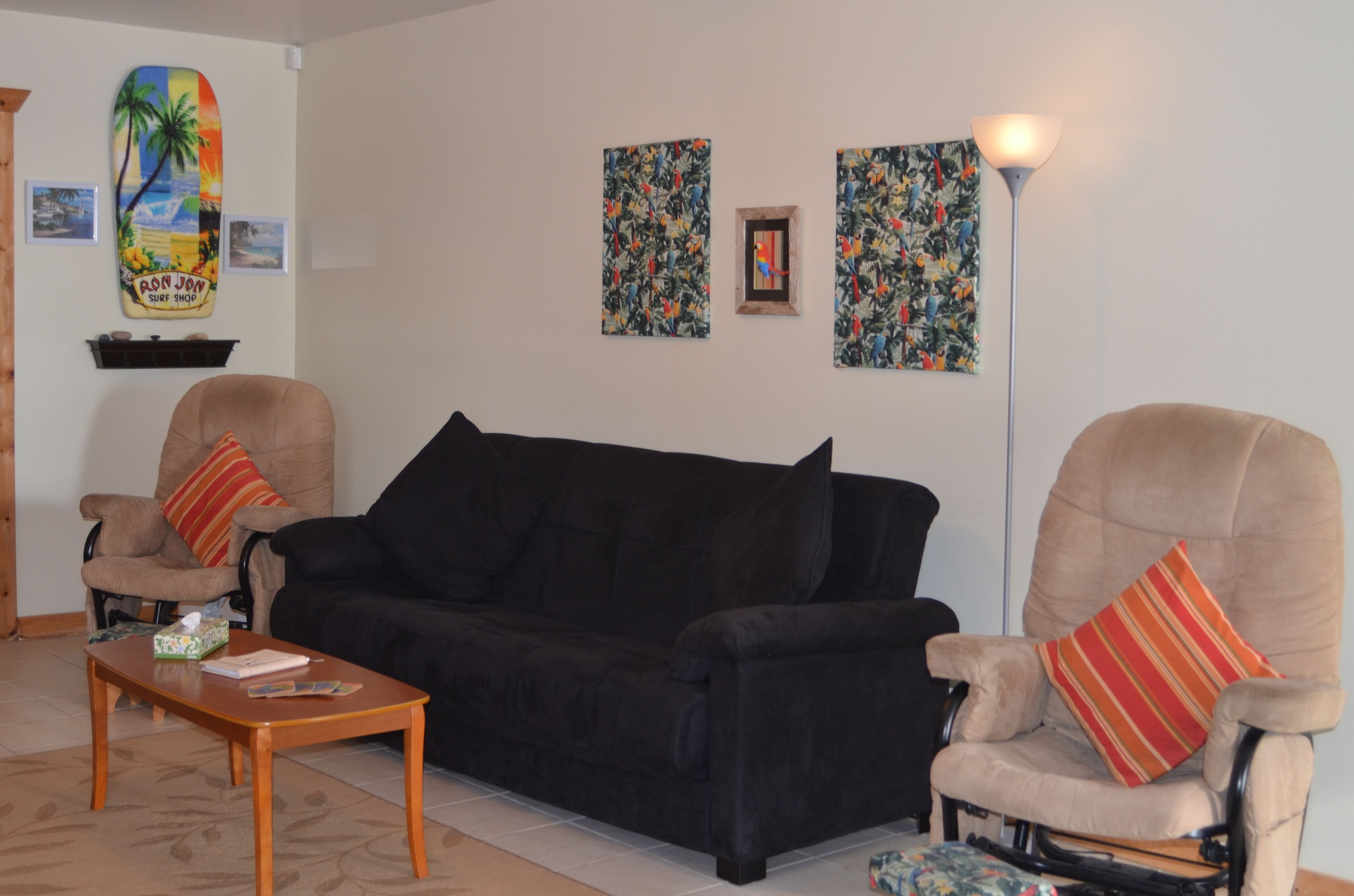 A living room with a black sofa, two armchairs, a wooden coffee table, and a floor lamp.