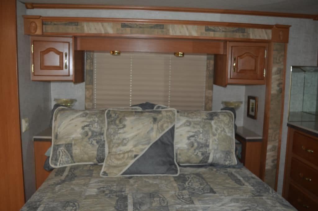 A bedroom with a bed, patterned bedding, and wooden cabinetry.
