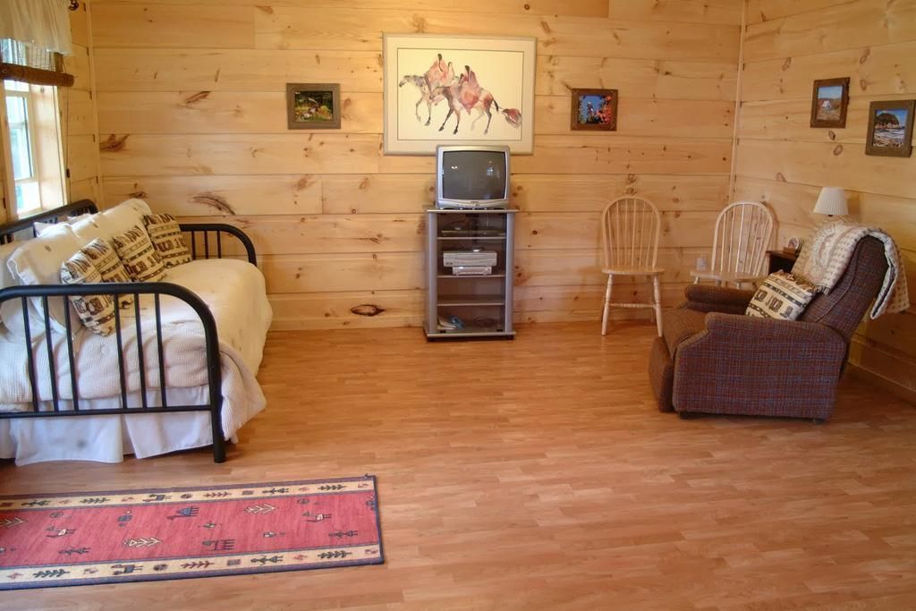 A cozy room with a bed, a chair, a small TV, and a rug.